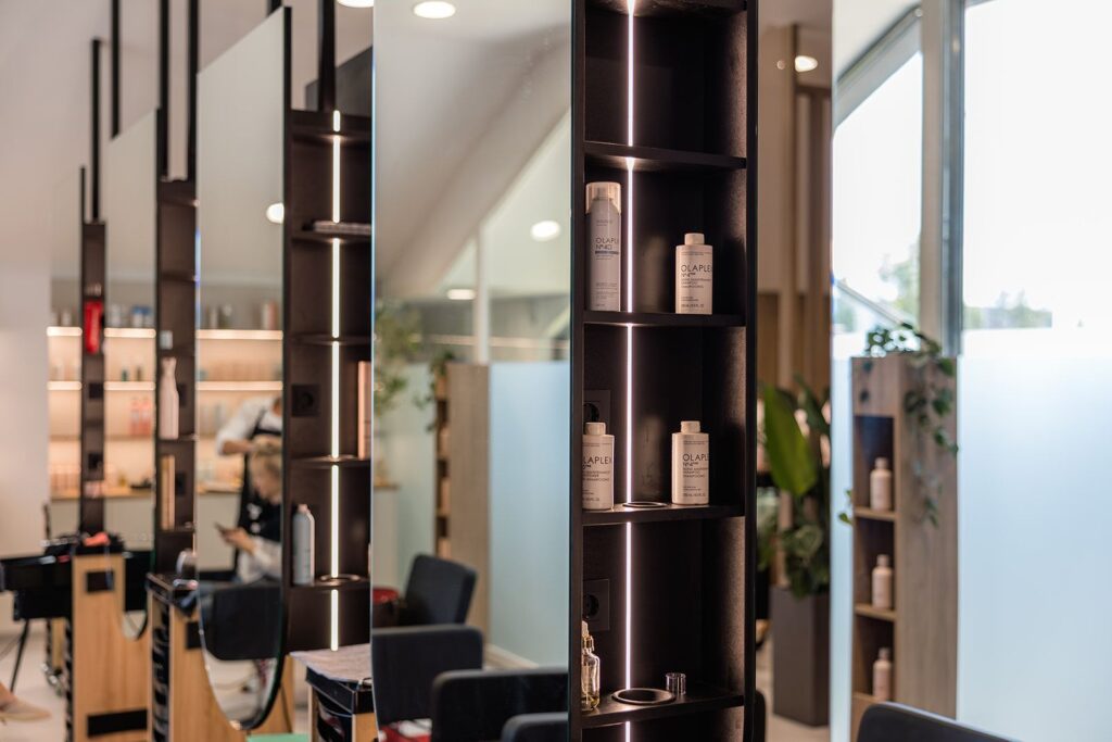 Frizerski salon z regali, ogledali in steklenimi pregradami