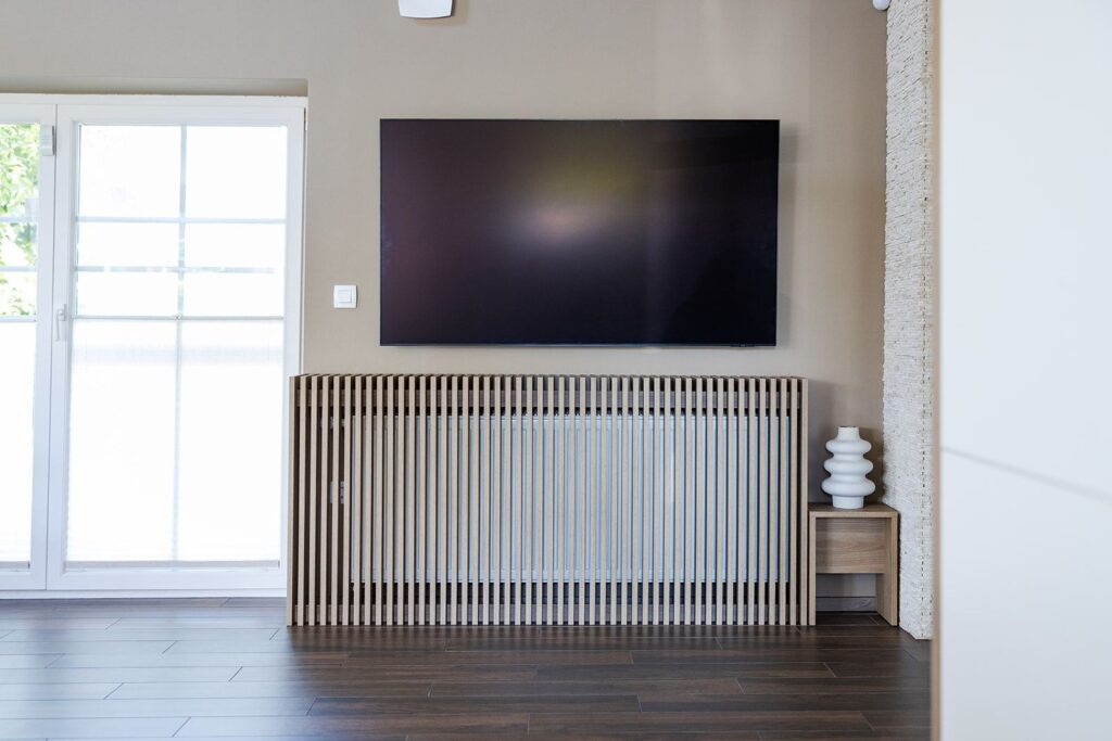Dnevni prostor s televizorjem nad letvično oblogo radiatorja