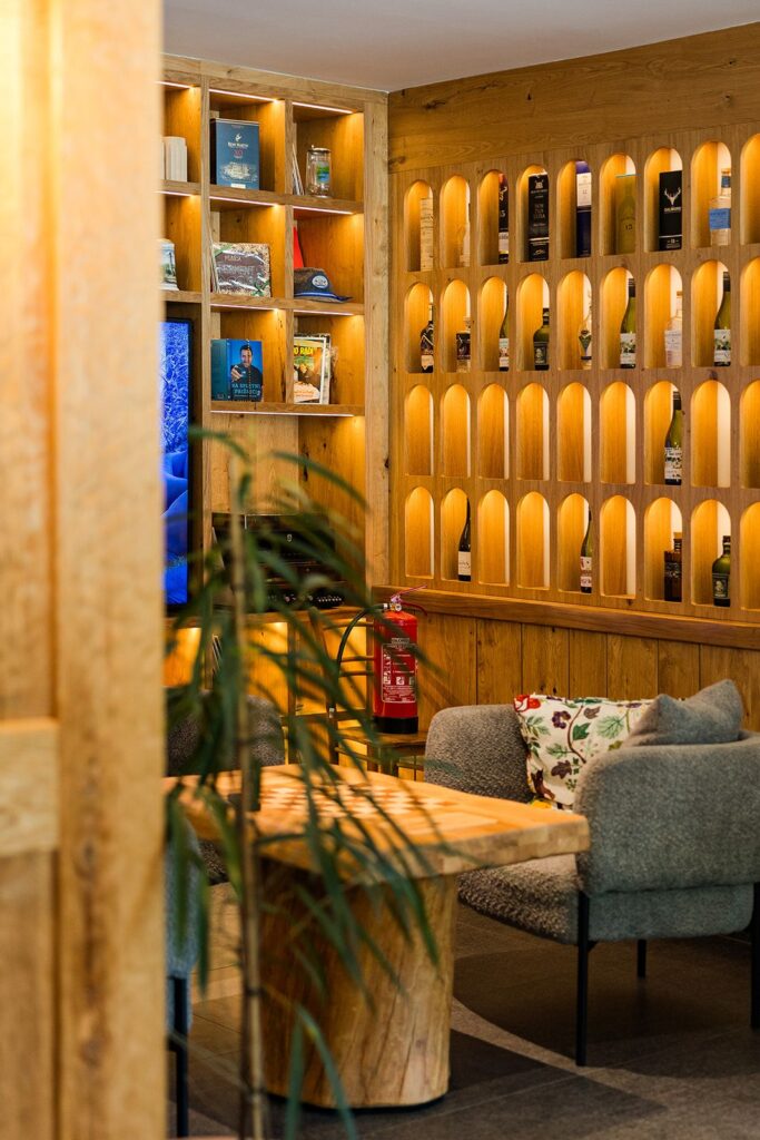 Osvetljene police z vinom in lounge kotiček s fotelji